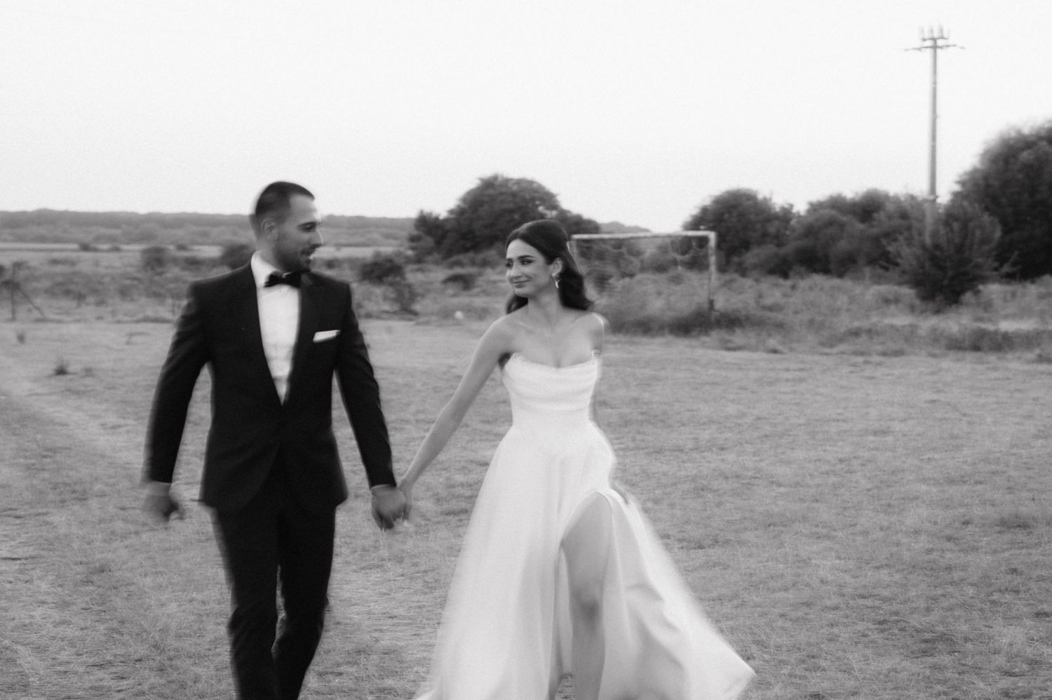A bride and groom share romantic moments in an open field with golden sunlight behind them.