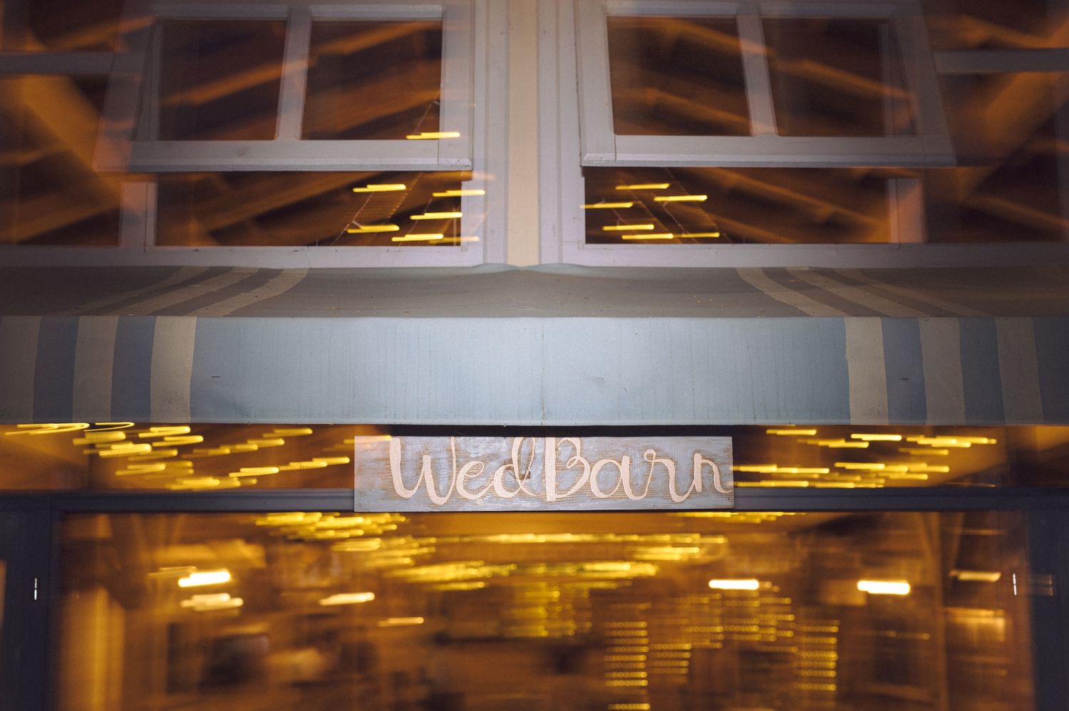 Illuminated signage and architectural details seen through a structural window or opening with warm lighting.
