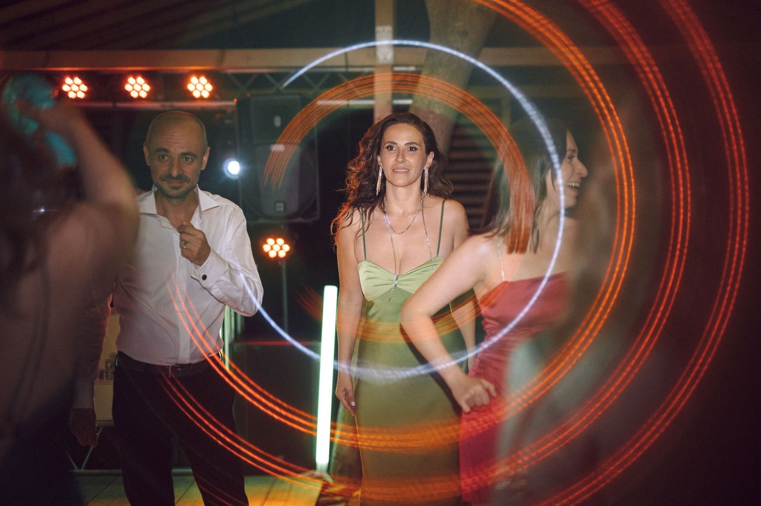 A blurry photo shows people dancing in a dimly lit venue with orange lighting effects in the background.