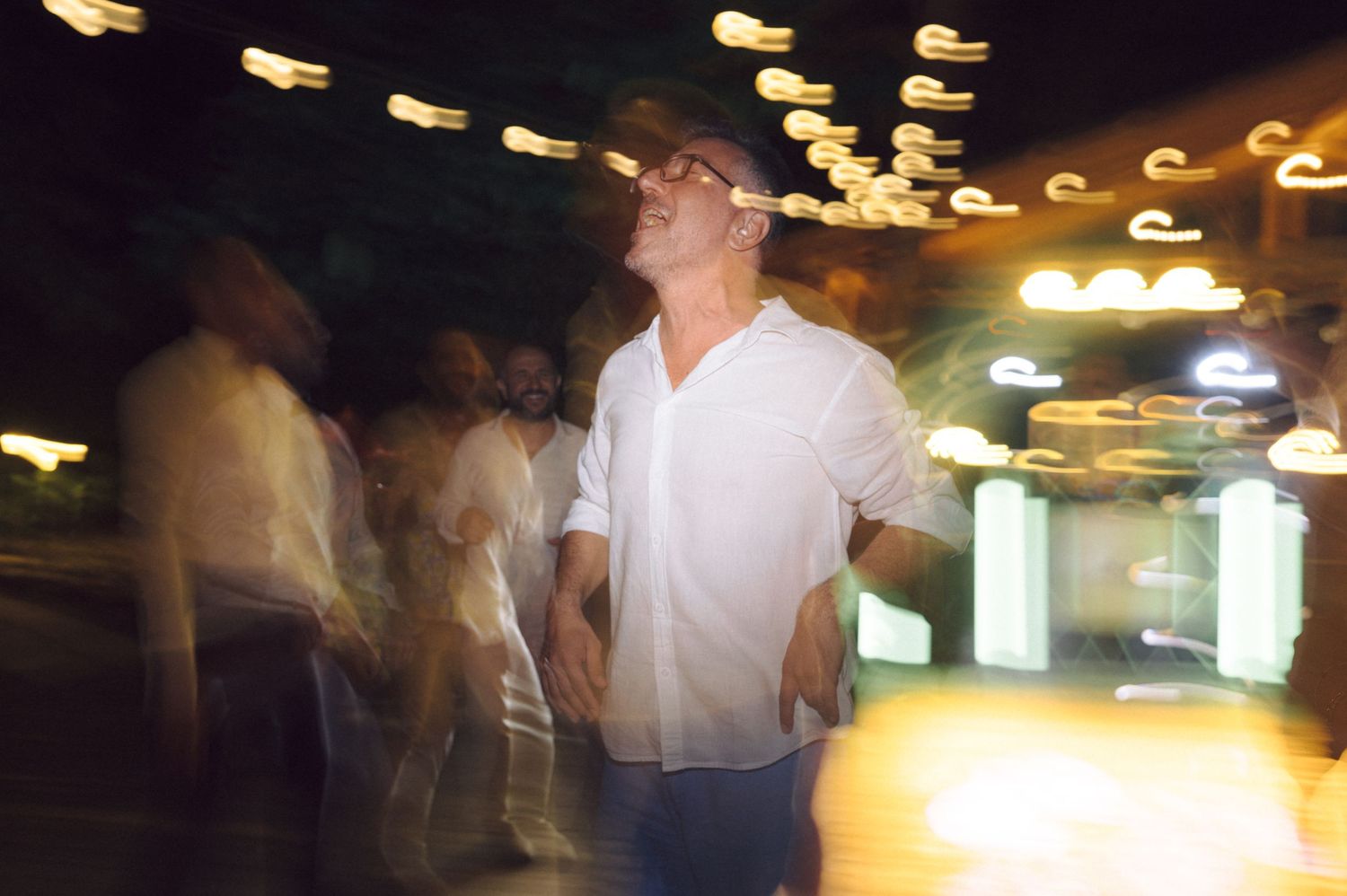 People dancing and mingling at a dimly lit party venue with glowing ceiling lights creating an atmospheric mood.