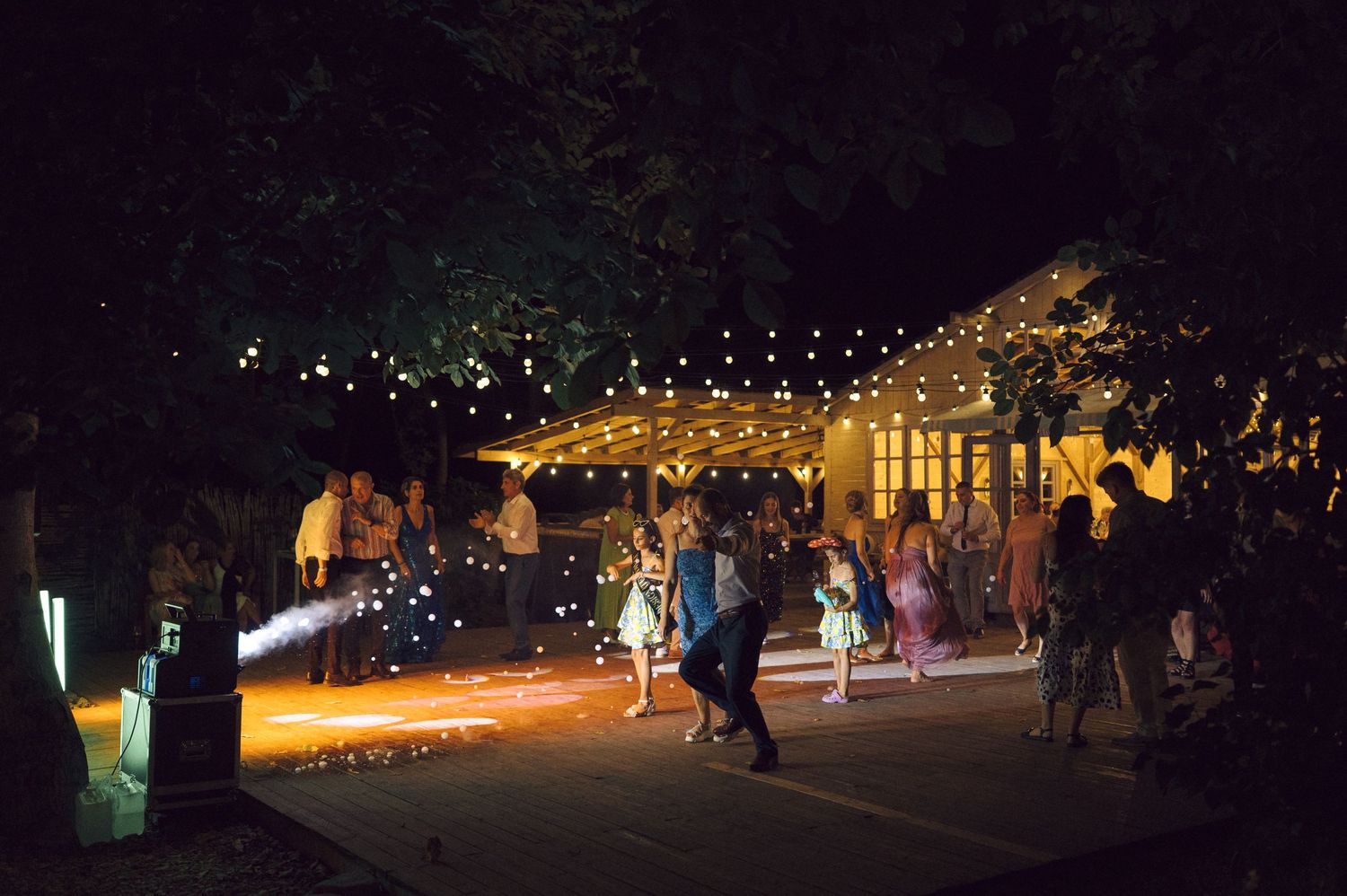 Long exposure photo of illuminated winter light displays and walkways in a dark outdoor garden setting at night.