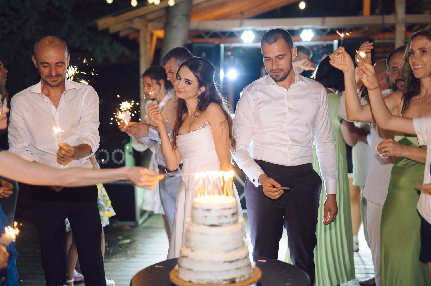 A collage of wedding reception photos showing guests celebrating with sparklers and a candlelit birthday cake.