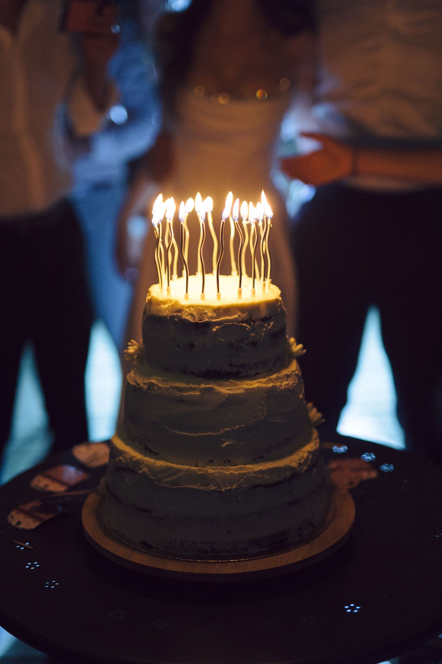 A dark chocolate birthday cake with glowing candles shown in a time-lapse sequence from unlit to fully illuminated.