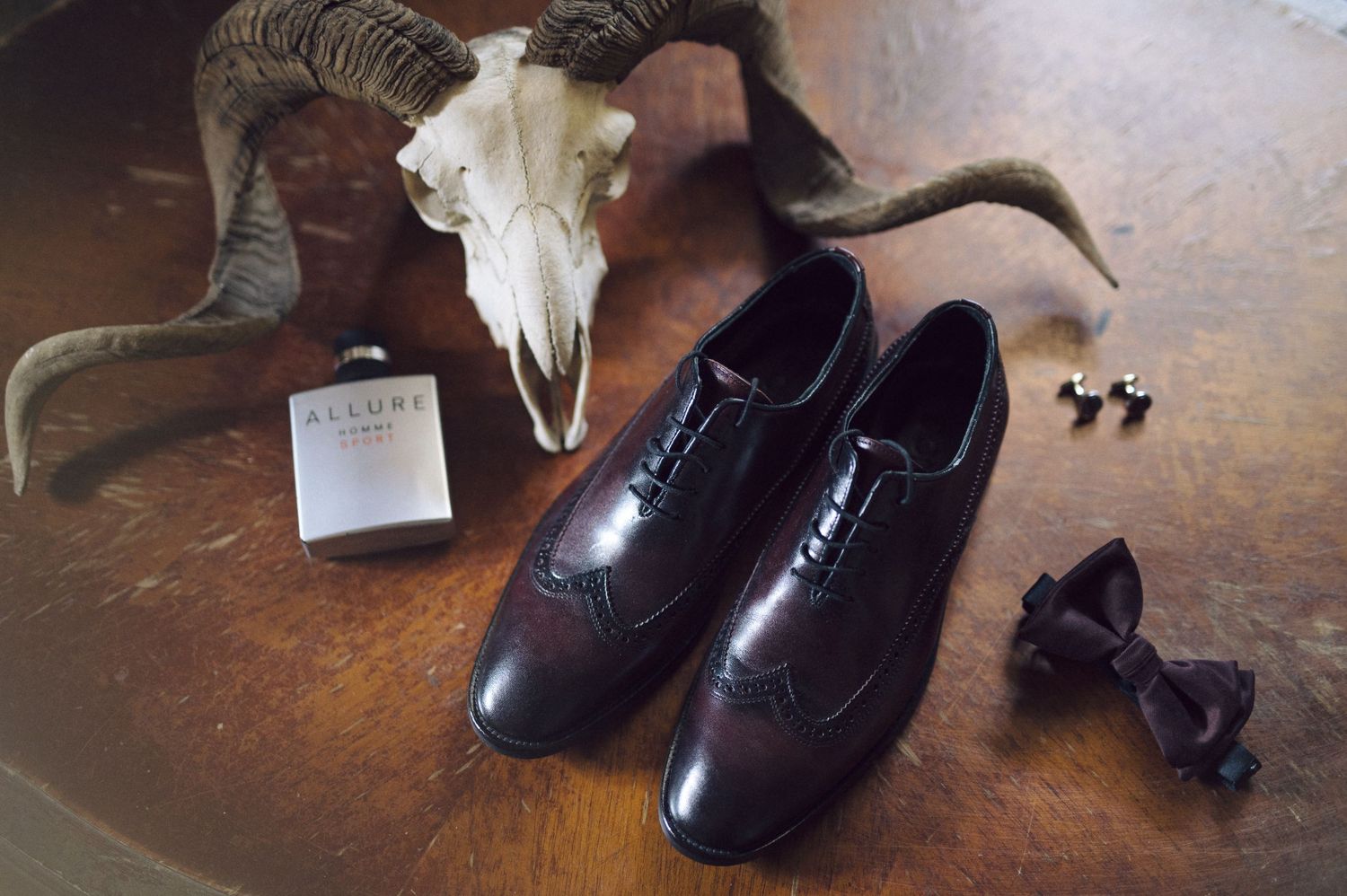 Black leather dress shoes displayed on wooden surface with varying lighting and angles.
