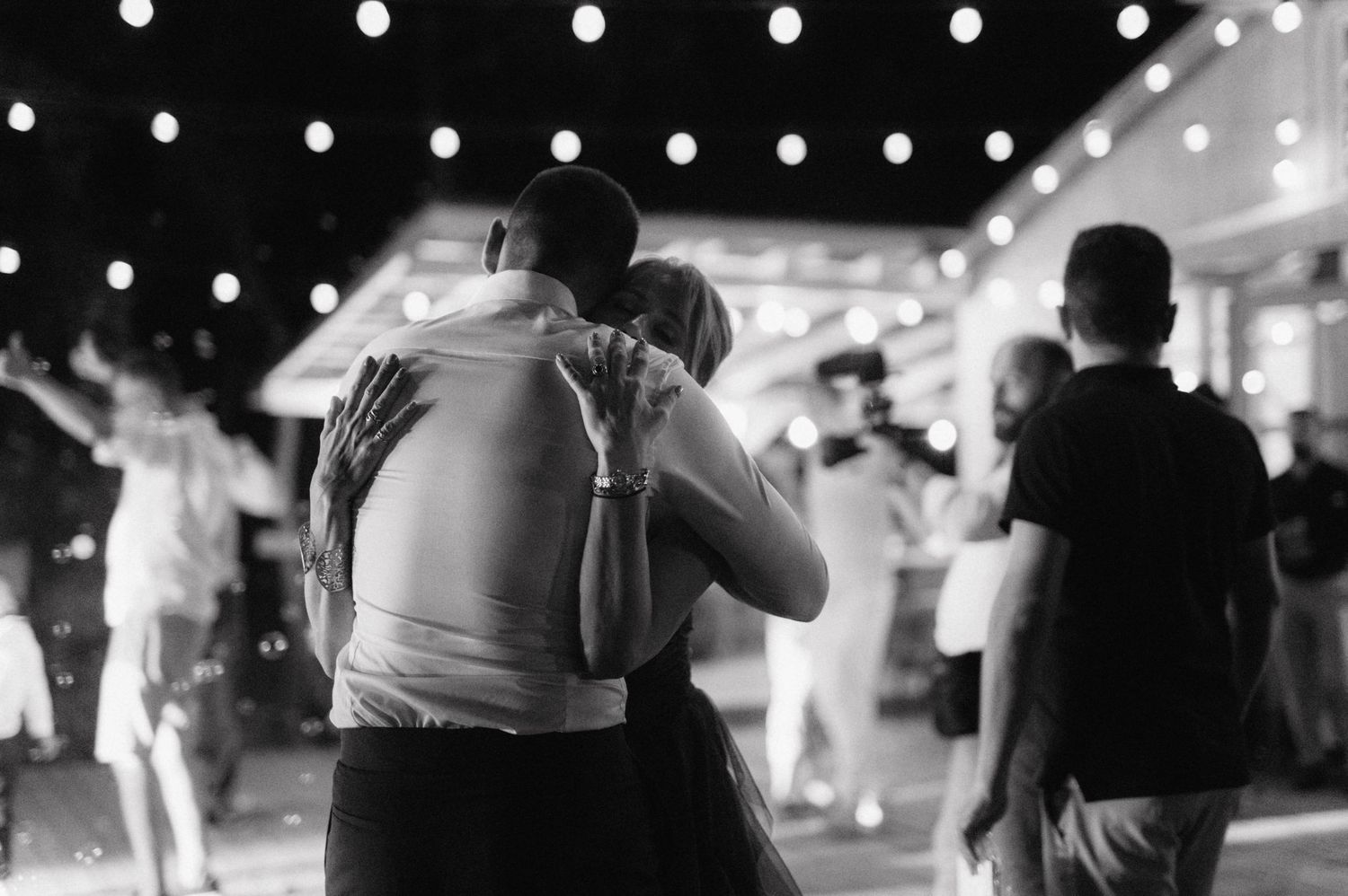 People dance together in a dimly lit venue with twinkling lights creating a romantic atmosphere.