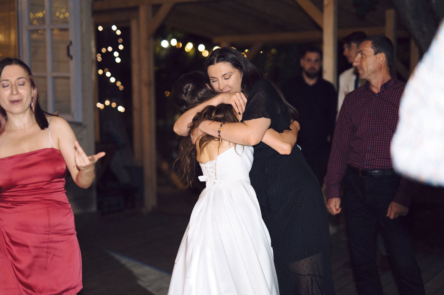 Guests dancing and celebrating at an elegant evening wedding reception with people in formal red dresses and white gowns.