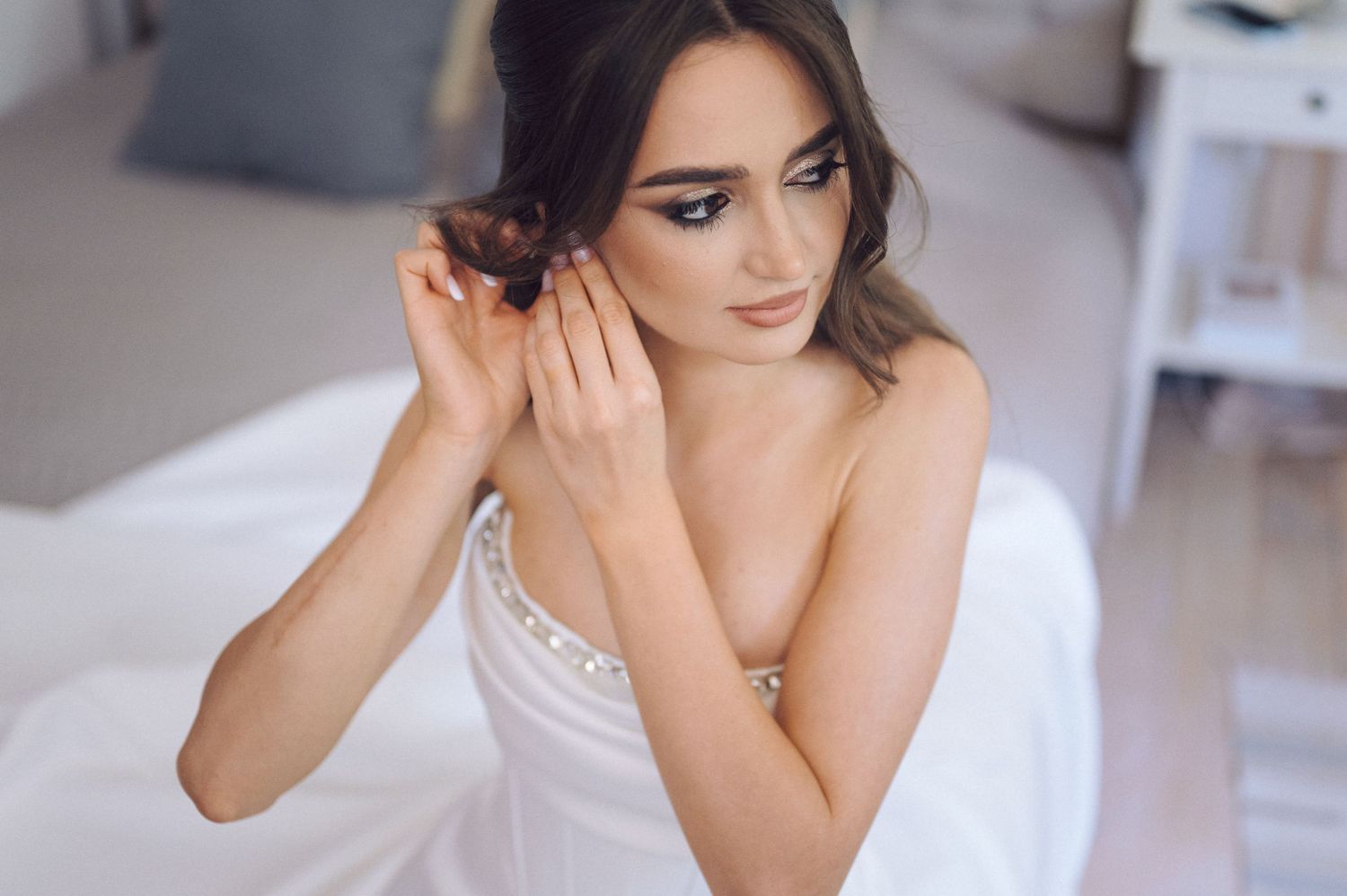 A person wearing a white corset top poses gracefully in a bright indoor setting with elegant decor.