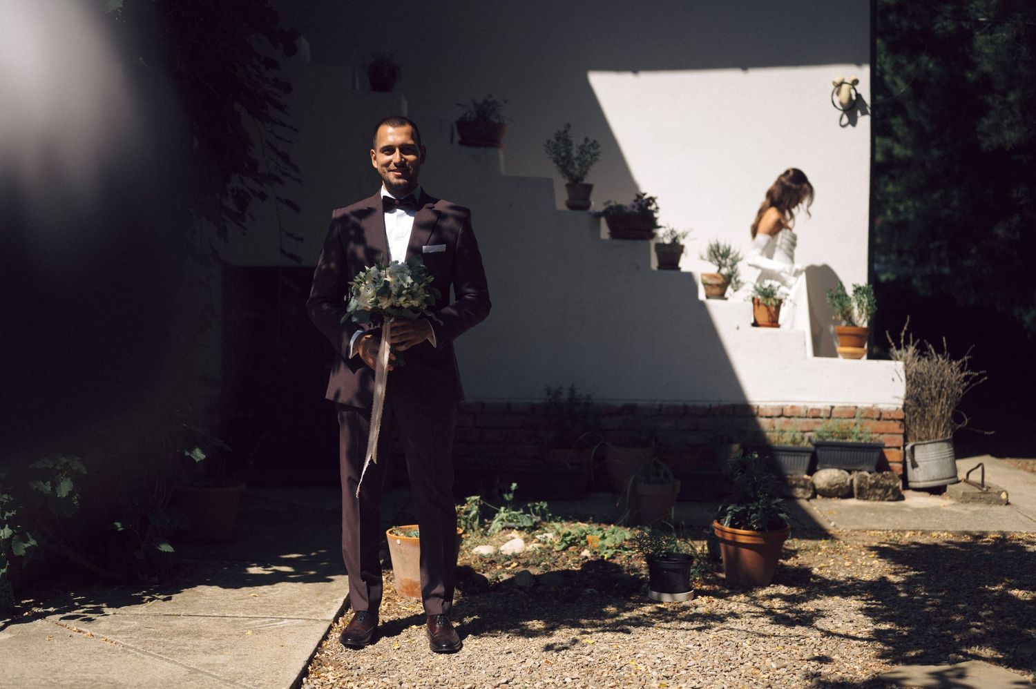 A vintage splitscreen view of someone walking down a sunny path with shadows cast across white walls outdoors.