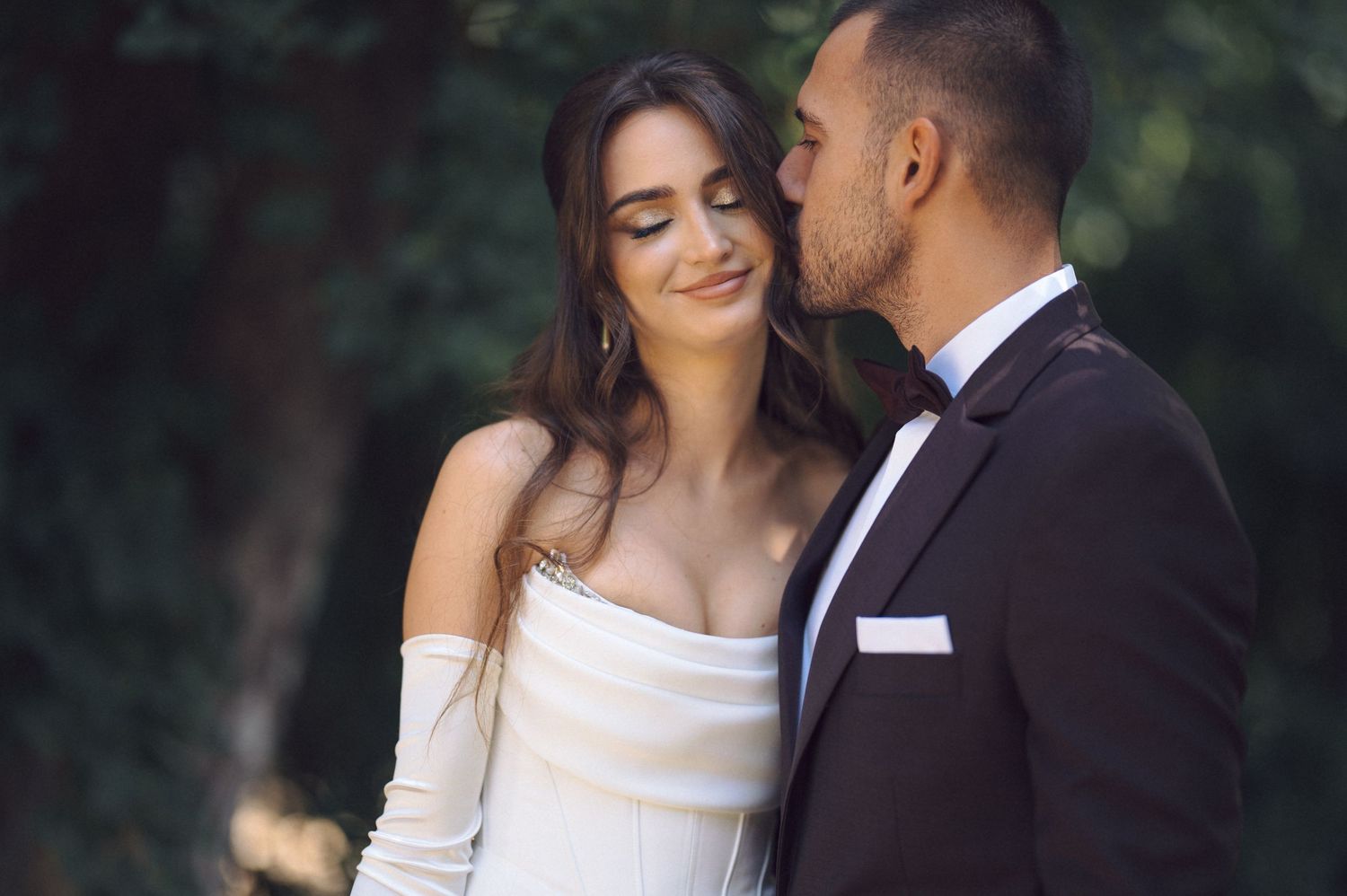 A romantic wedding couple embraces tenderly in a lush garden setting during their outdoor photo session.