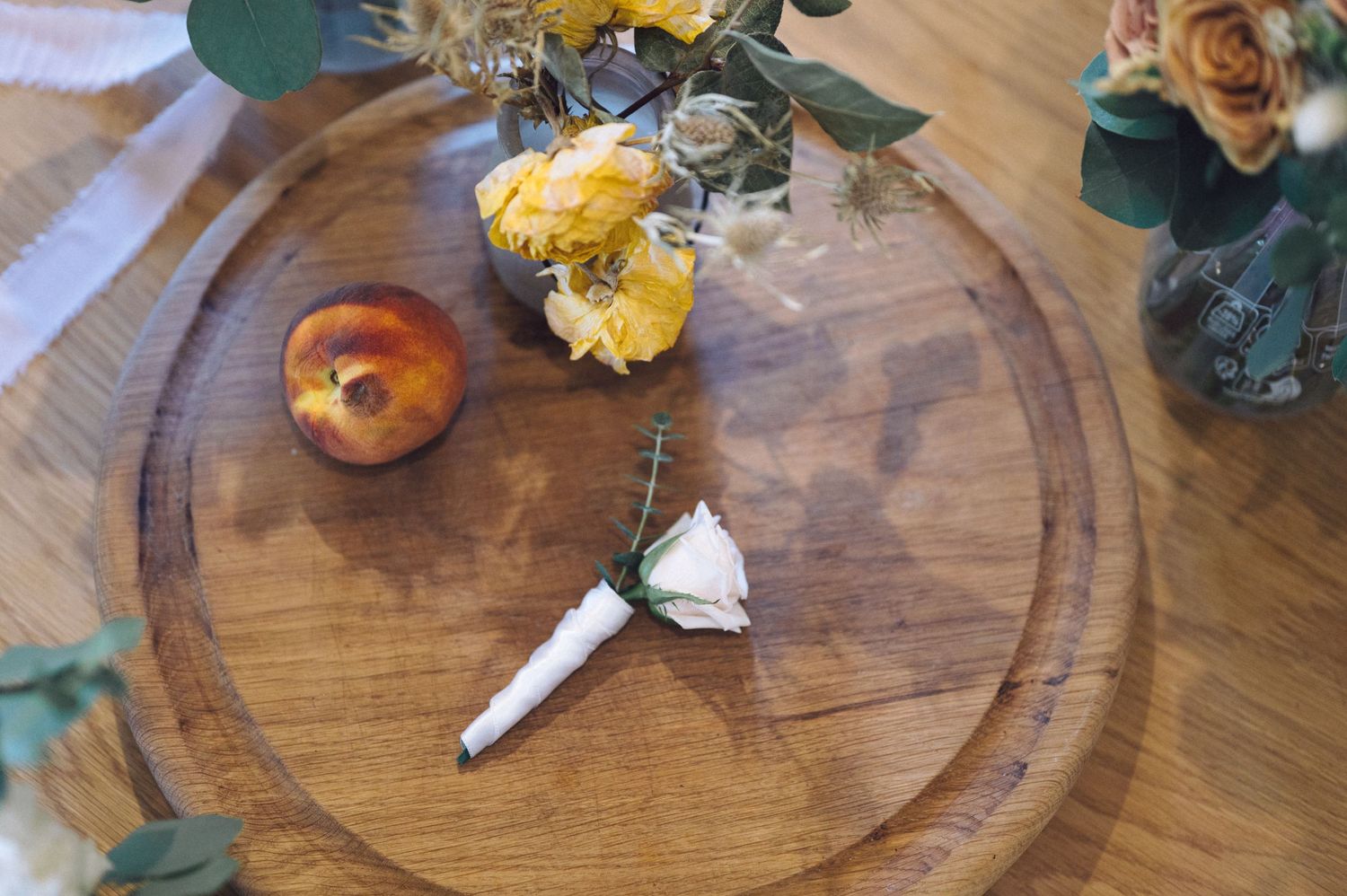 Elegant wedding details with peach roses and rings displayed on a rustic wooden surface.