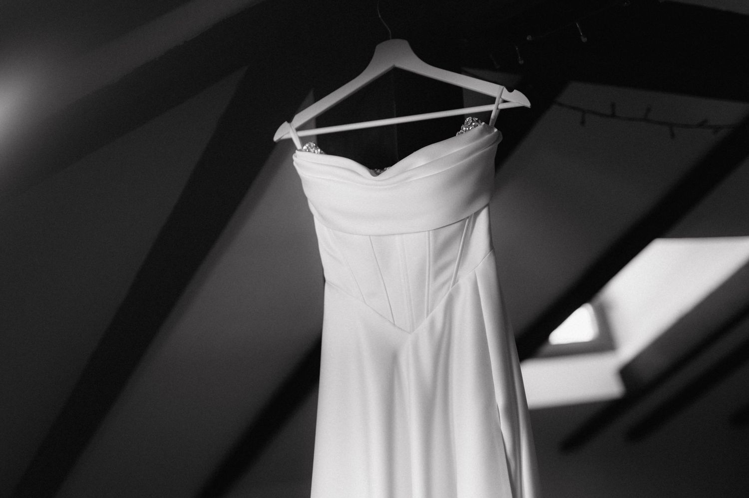 Eight close-up detail shots of a white strapless wedding dress hanging on display show delicate fabric and design elements.