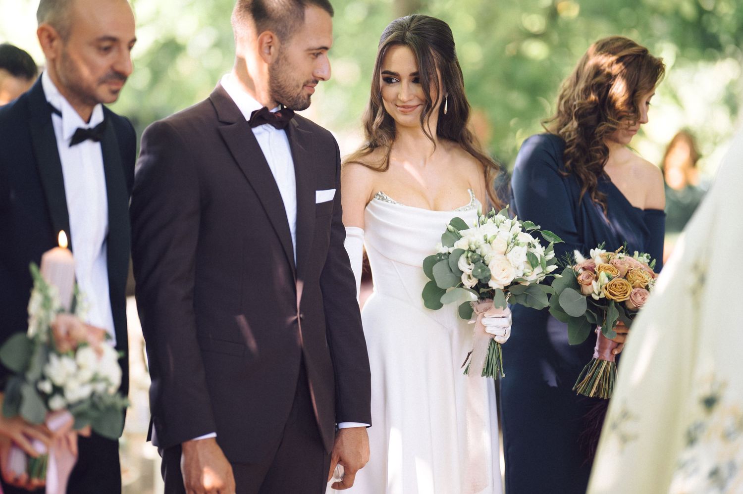 Elegant outdoor wedding celebration with stylishly-dressed guests mingling and socializing at a garden venue.