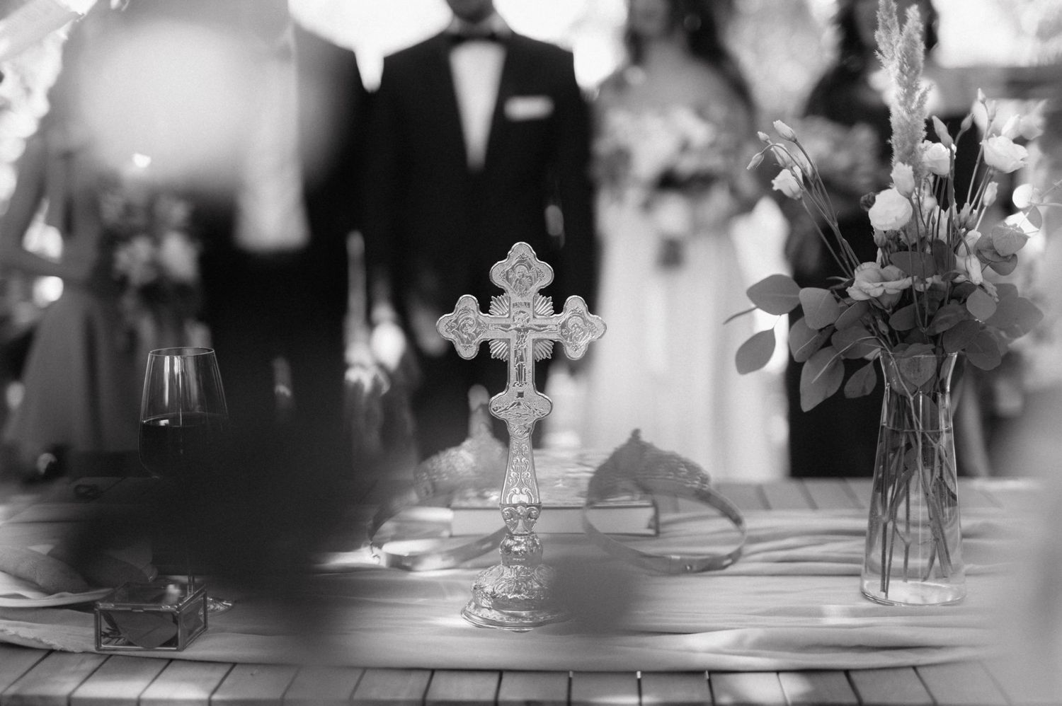 Black and white reception table settings with floral centerpieces and ornate cross decorations create an elegant atmosphere.