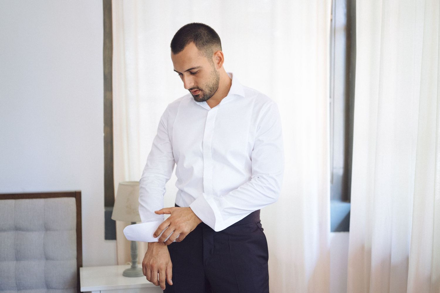 A person in a white dress shirt sits at a table reading a document.