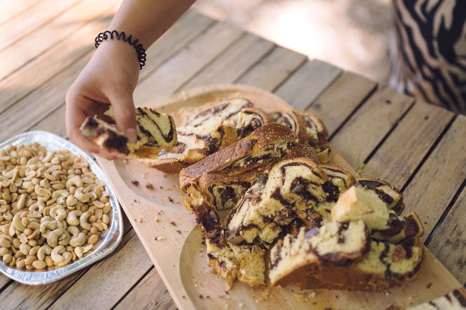 Hands assemble an open-faced sandwich with sliced mushrooms and melted cheese on crusty bread.