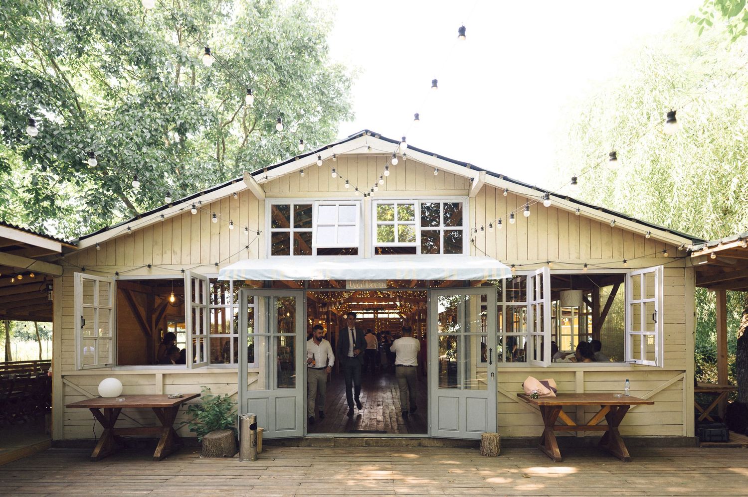 A series of connected pale yellow ranch-style buildings with white trim and shuttered windows in a wooded setting.
