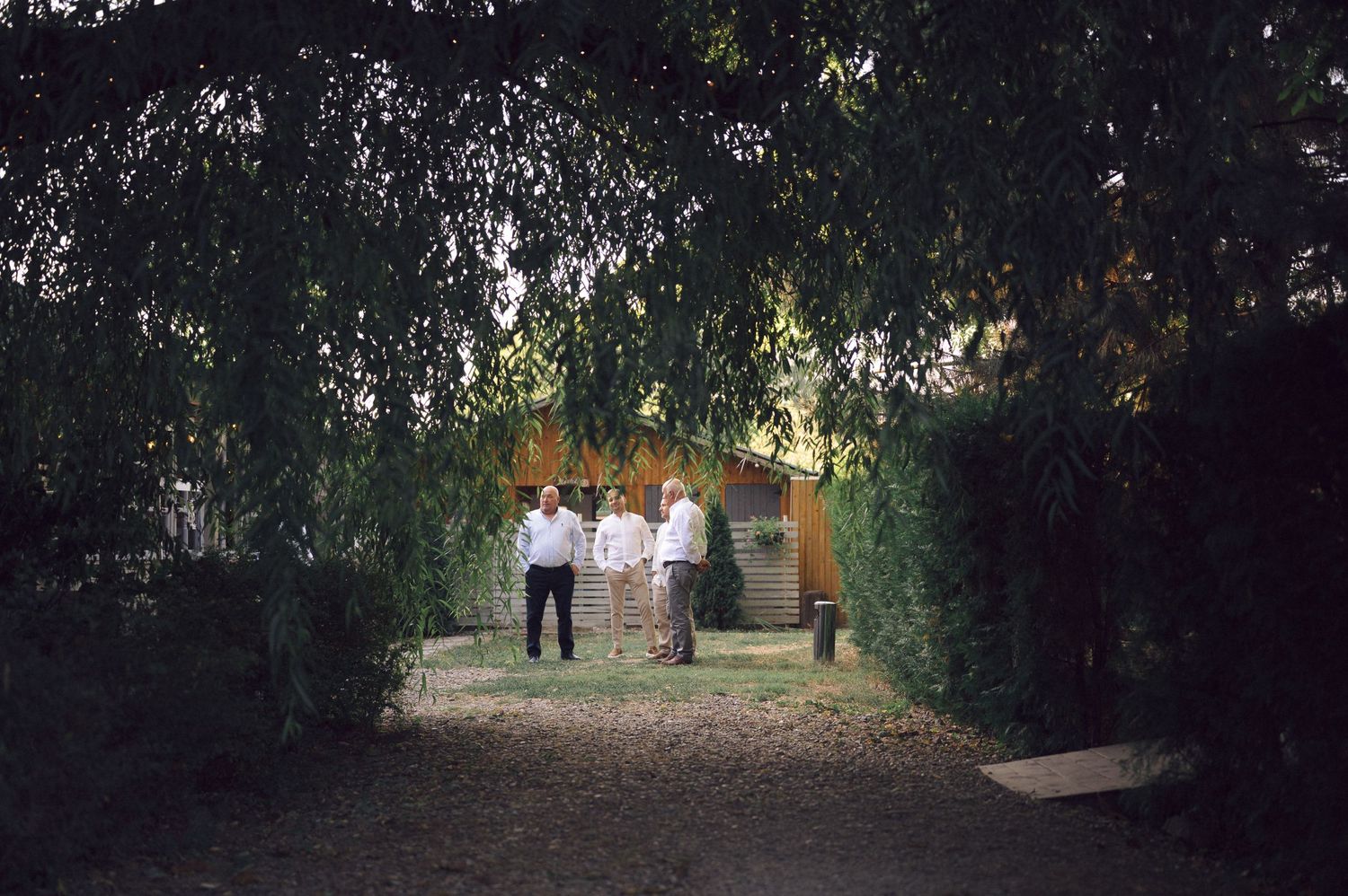Wedding guests gather beneath strings of lights in an outdoor garden setting.