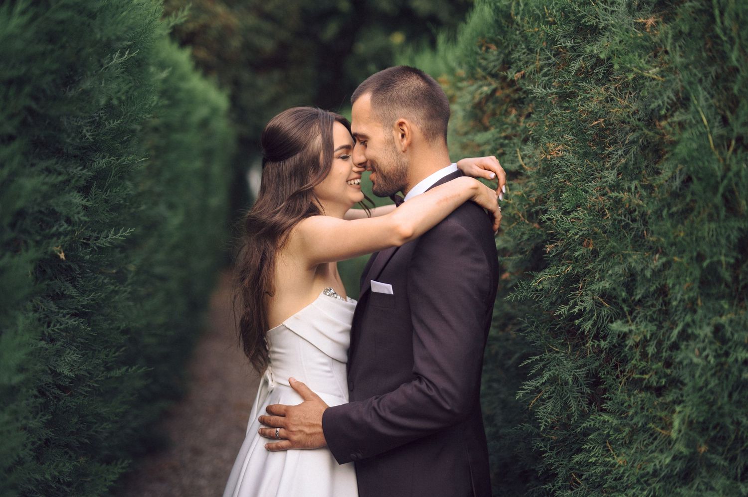 Intimate wedding moment captured between couple against lush greenery.