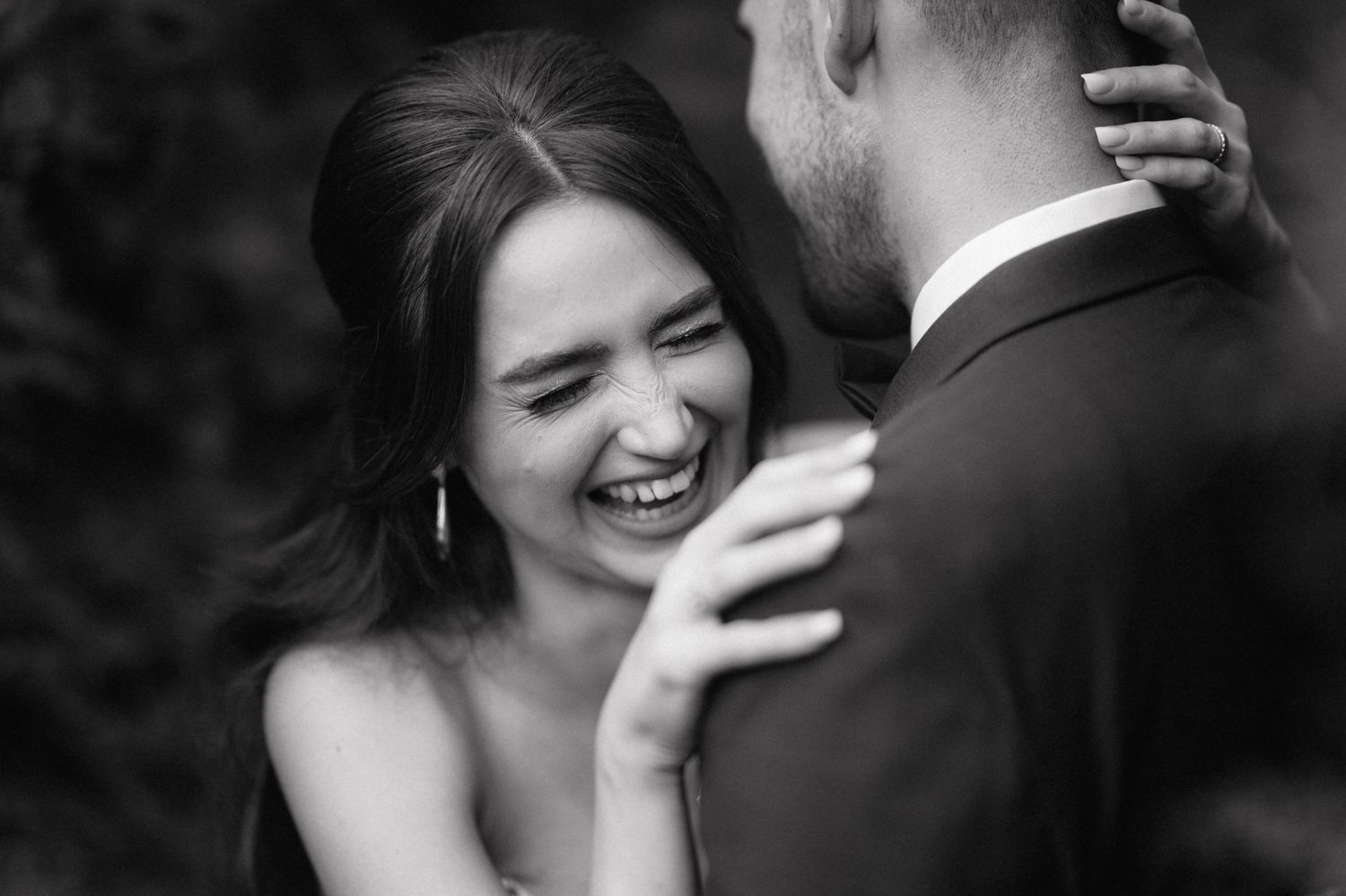 Black and white wedding photography showing tender embrace in garden setting.