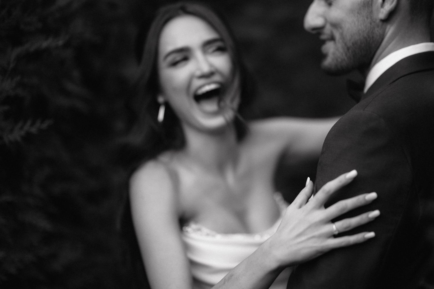 Joyful wedding couple sharing a laugh during their outdoor photo session.