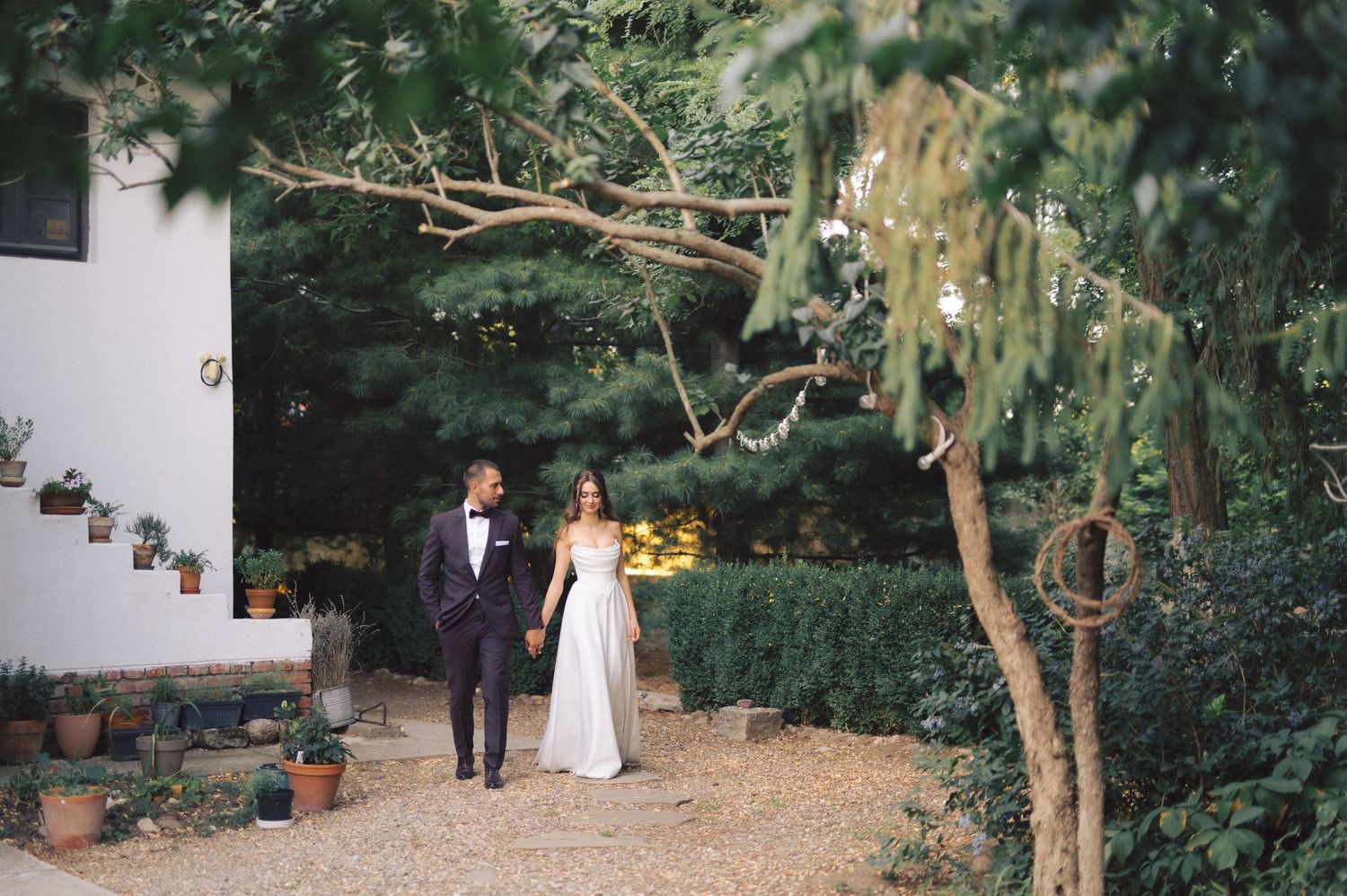 A romantic rustic garden wedding venue with lush greenery and hanging decorations creates an intimate atmosphere.