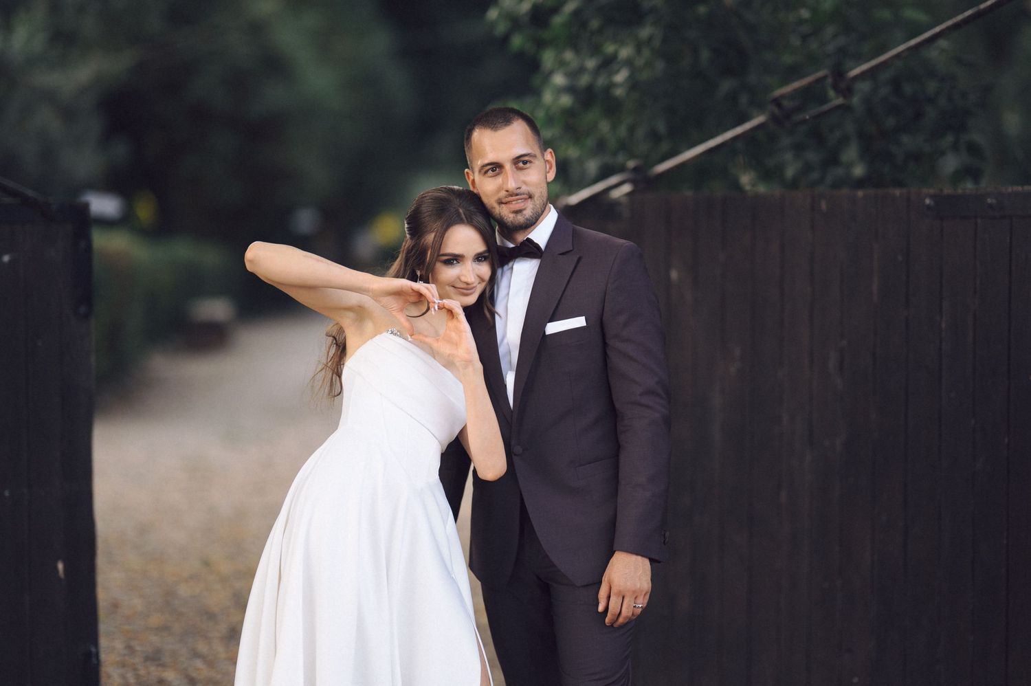 Wedding party walking outdoors in formal attire with bride in white dress and groom in dark suit.