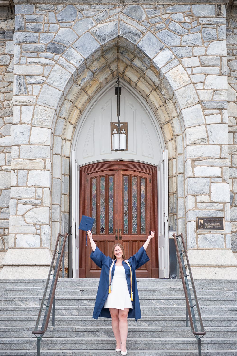 A celebratory pose on stone church steps in front of a Gothic arched doorway with white stone and wooden door.