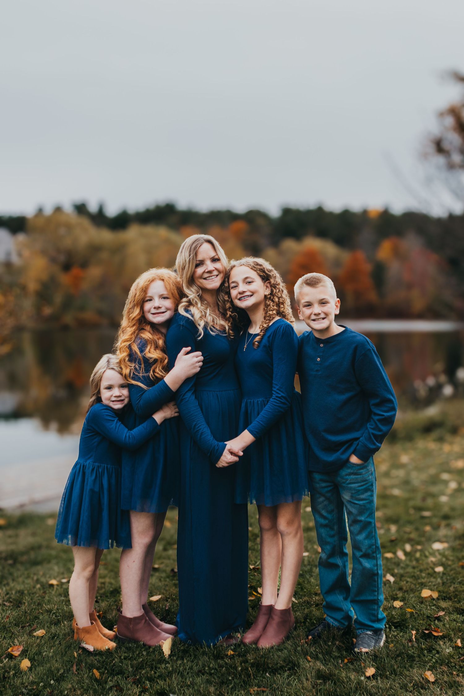 Family in coordinating blue and gray outfits poses together in a summer field.