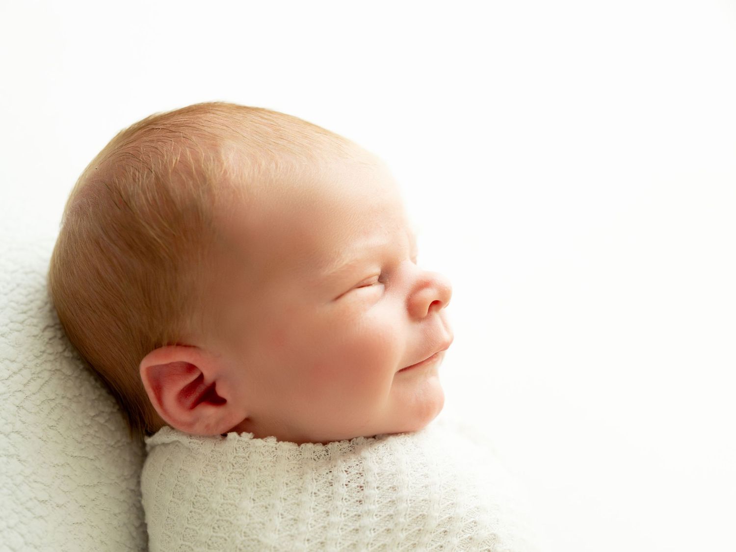 A sleeping infant rests in dreamy poses against a soft white backdrop, captured in a delicate newborn photography series.