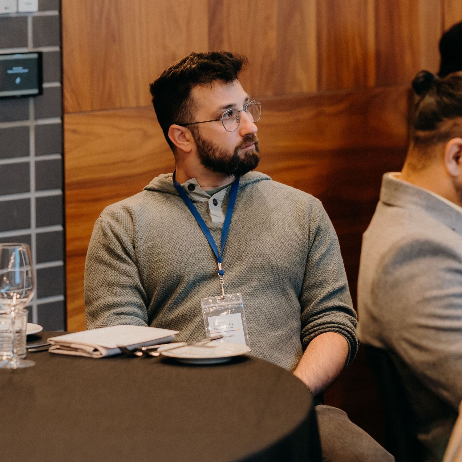 A side profile view of a person sitting in a conference room with wooden paneled walls.