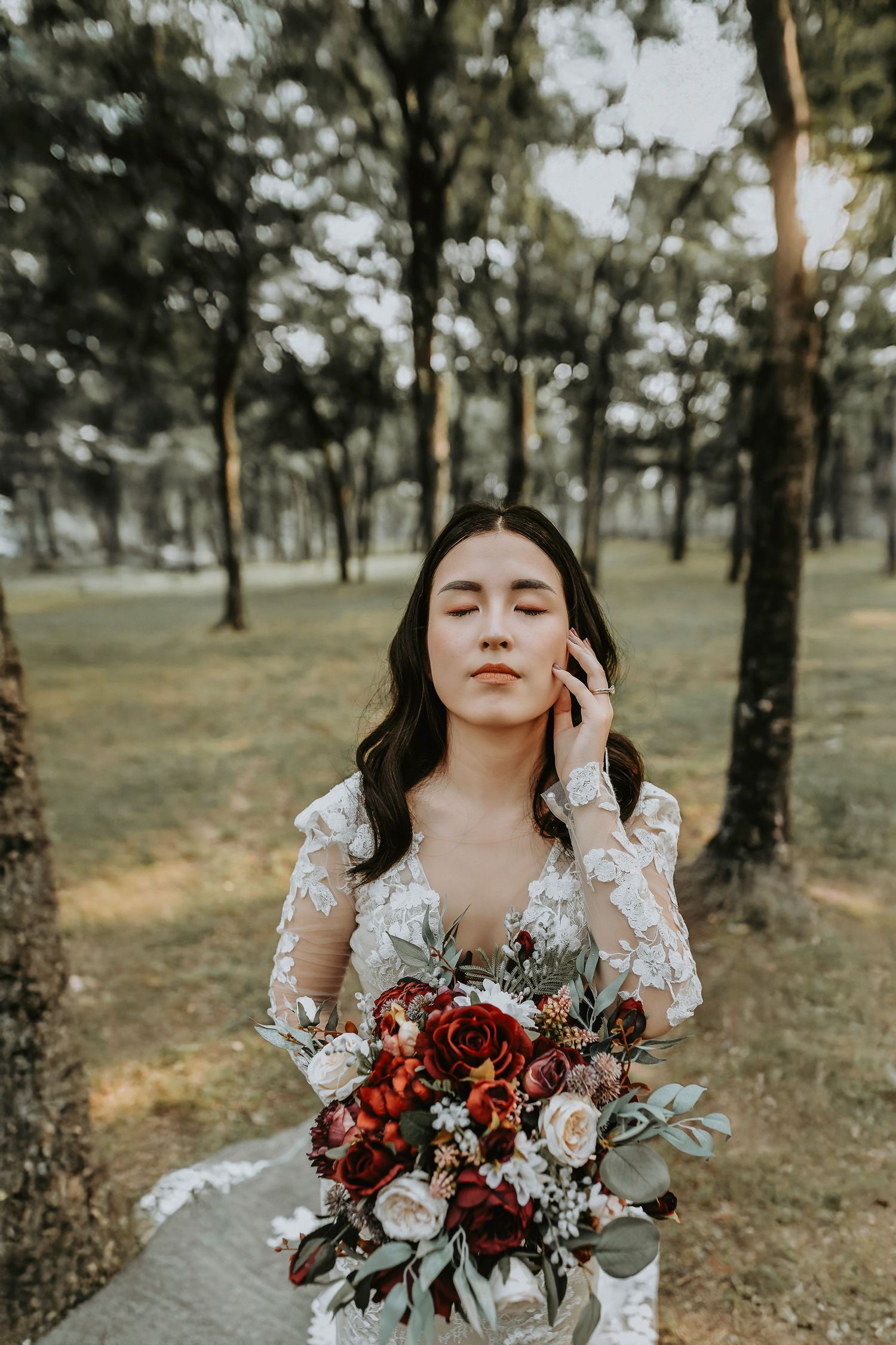 Golden hour bridal portrait with lace wedding dress and burgundy bouquet