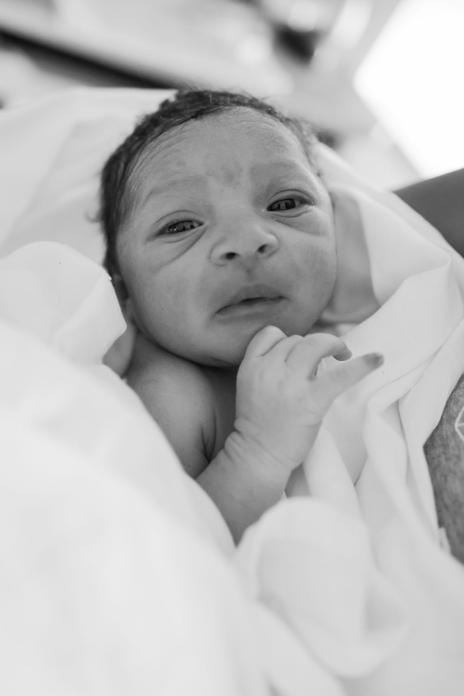 Close-up series of newborn baby wrapped in white blanket.