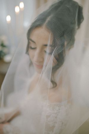 Ethereal bridal portrait through a delicate veil with soft lighting.