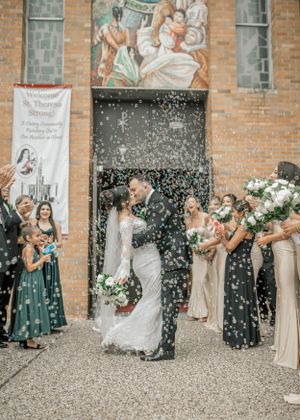 Bridal party celebrates outside brick church as newlyweds exit through shower of confetti in romantic ceremony.