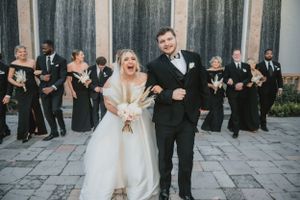 Wedding party celebrates on stone patio in Houston, TX with bridesmaids and groomsmen dancing behind happy couple in formal attire.