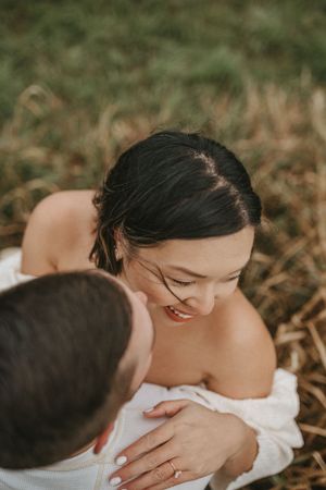 An intimate moment captured of a couple in a field showing off a wedding ring.