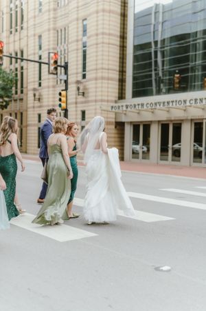 A bridal party in colorful dresses crosses the street near the Fort Worth Convention Center.