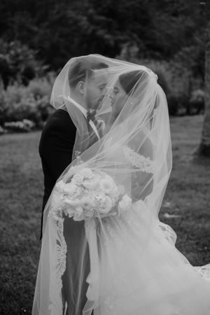 Romantic black and white portrait of a couple beneath a flowing veil.