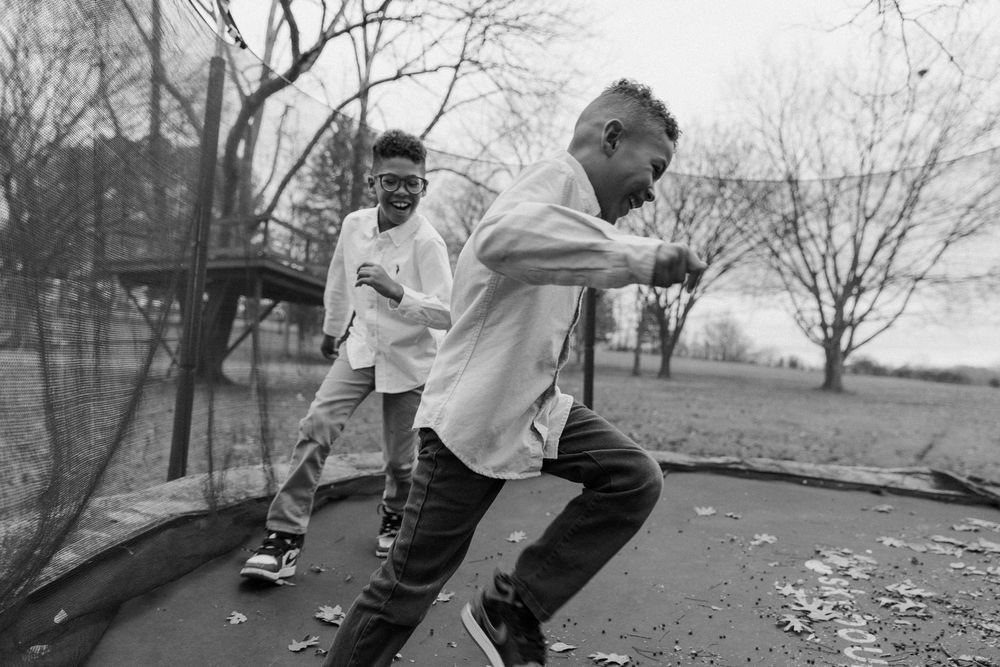 2 brothers playing on the trampoline in a black and white photo.
