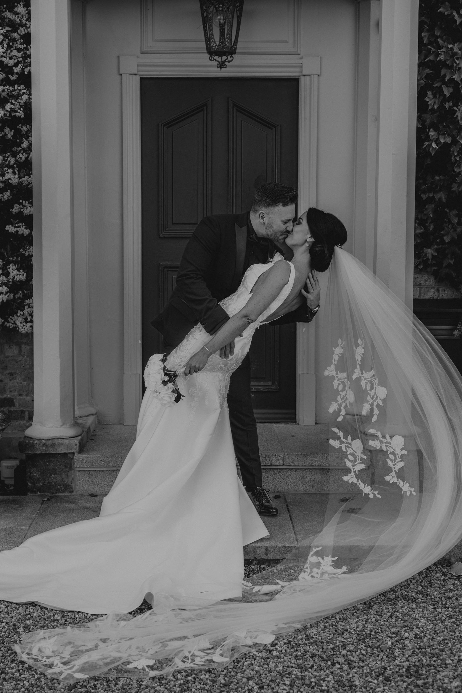 A dramatic black and white wedding photo with a couple in an elegant dip pose.