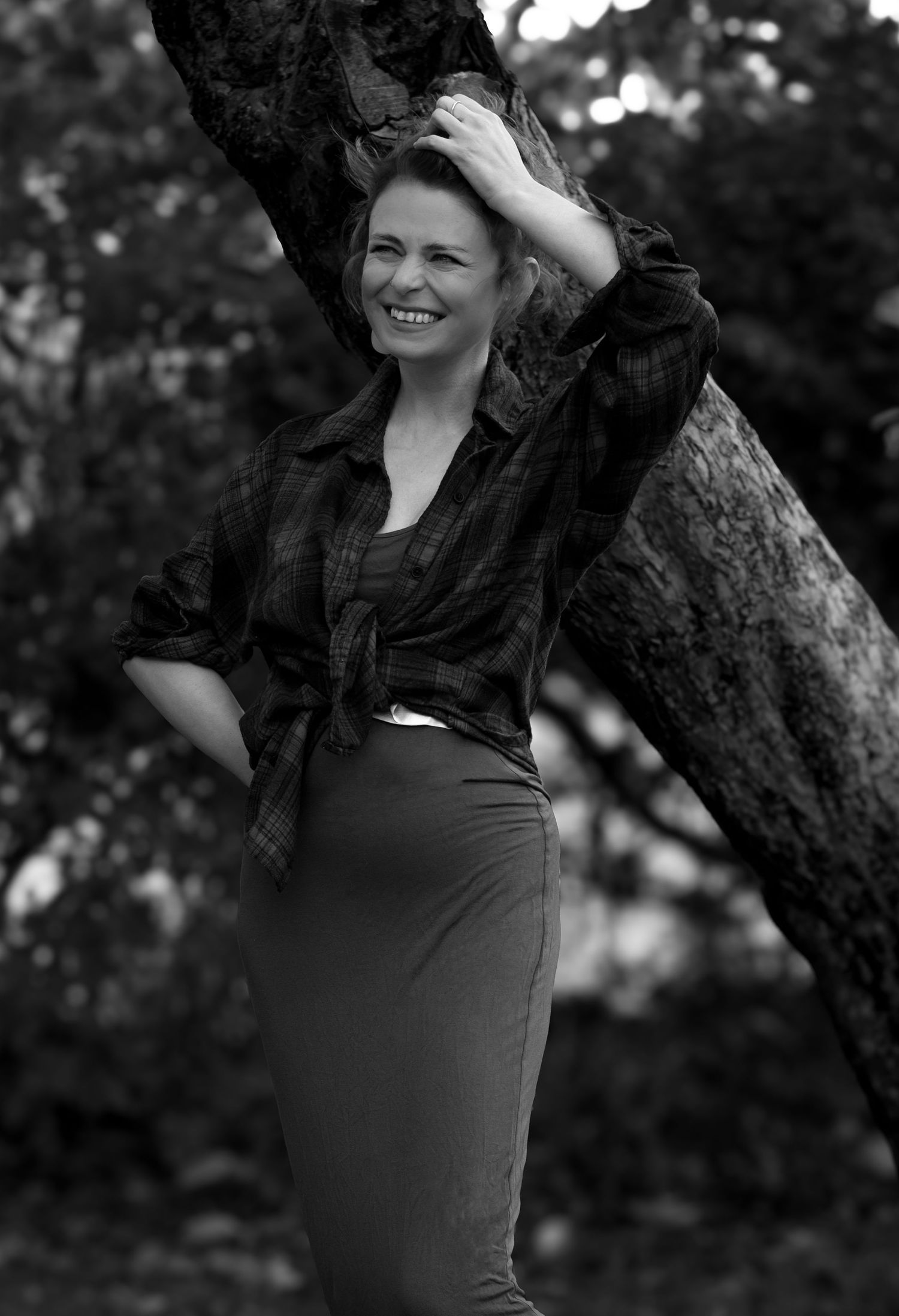Tammy Rhymer in a rural environment smiling into the distance with her hand on her head.