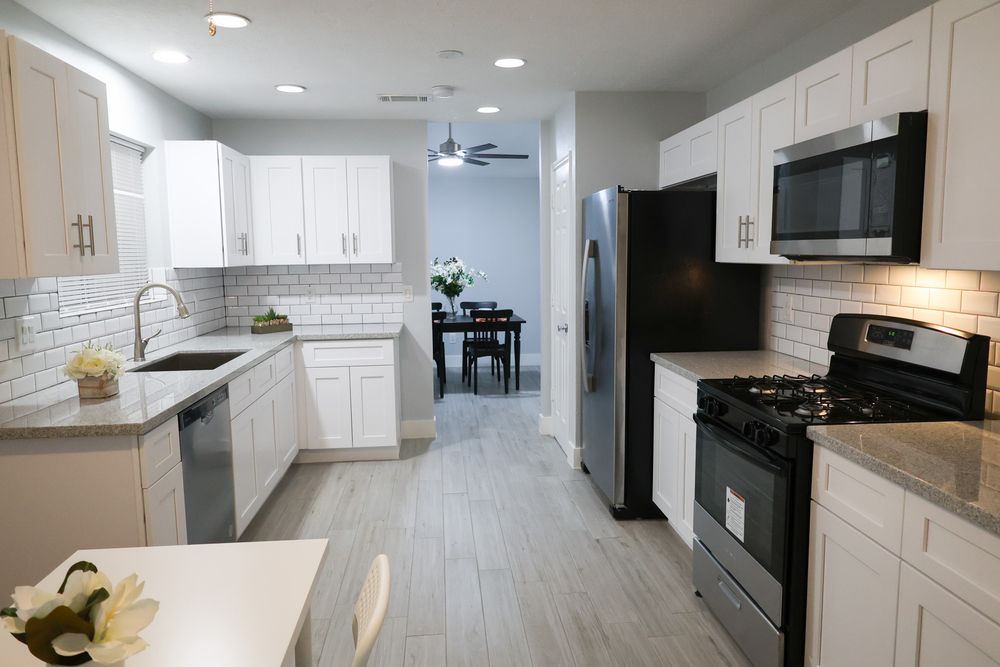 Sleek modern kitchen with white cabinets, black appliances, and open concept layout.