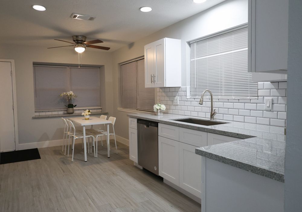 Bright modern kitchen with white subway tile backsplash and ceiling fan.