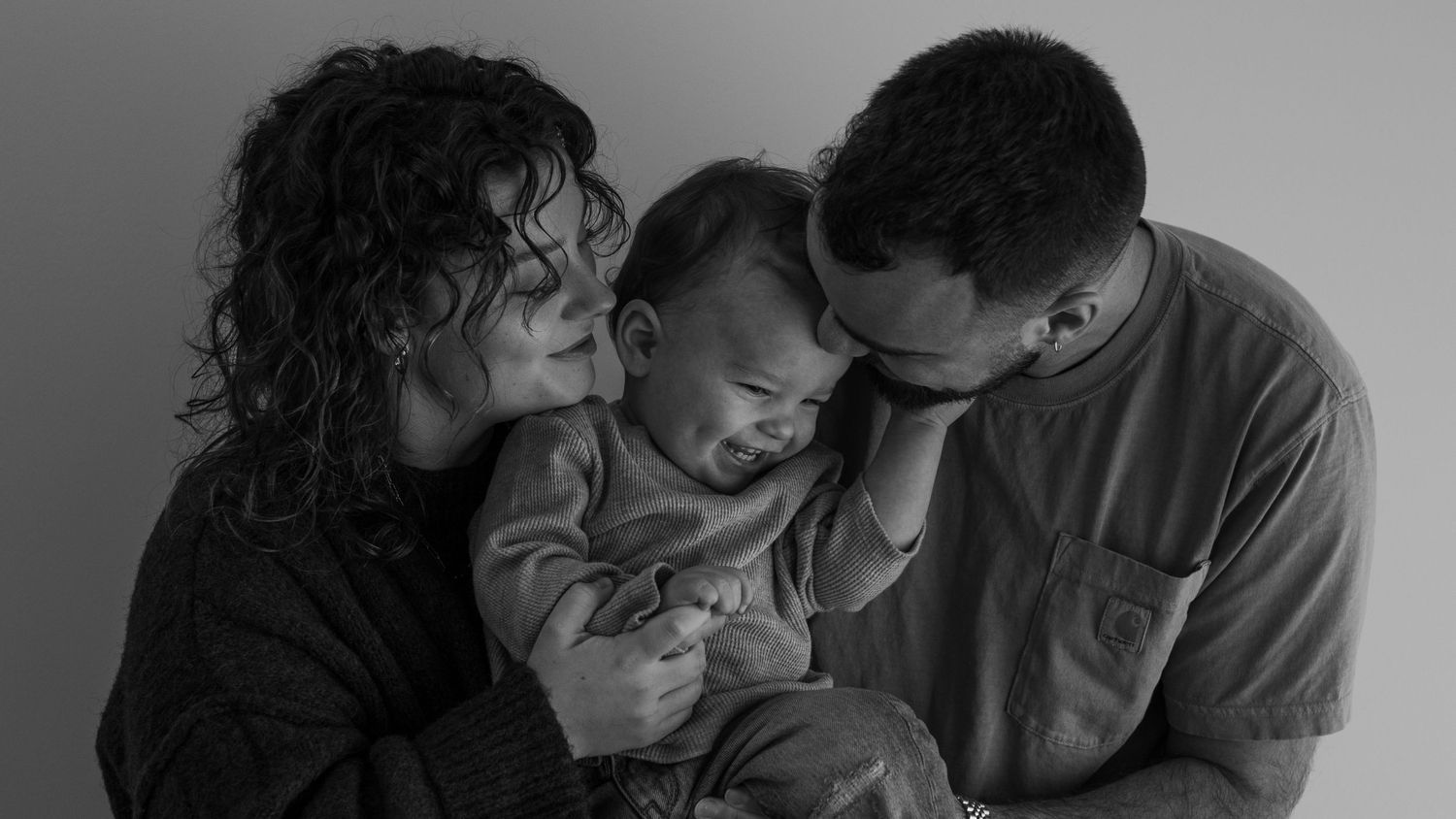 An intimate black and white portrait of three people sharing a tender moment together.