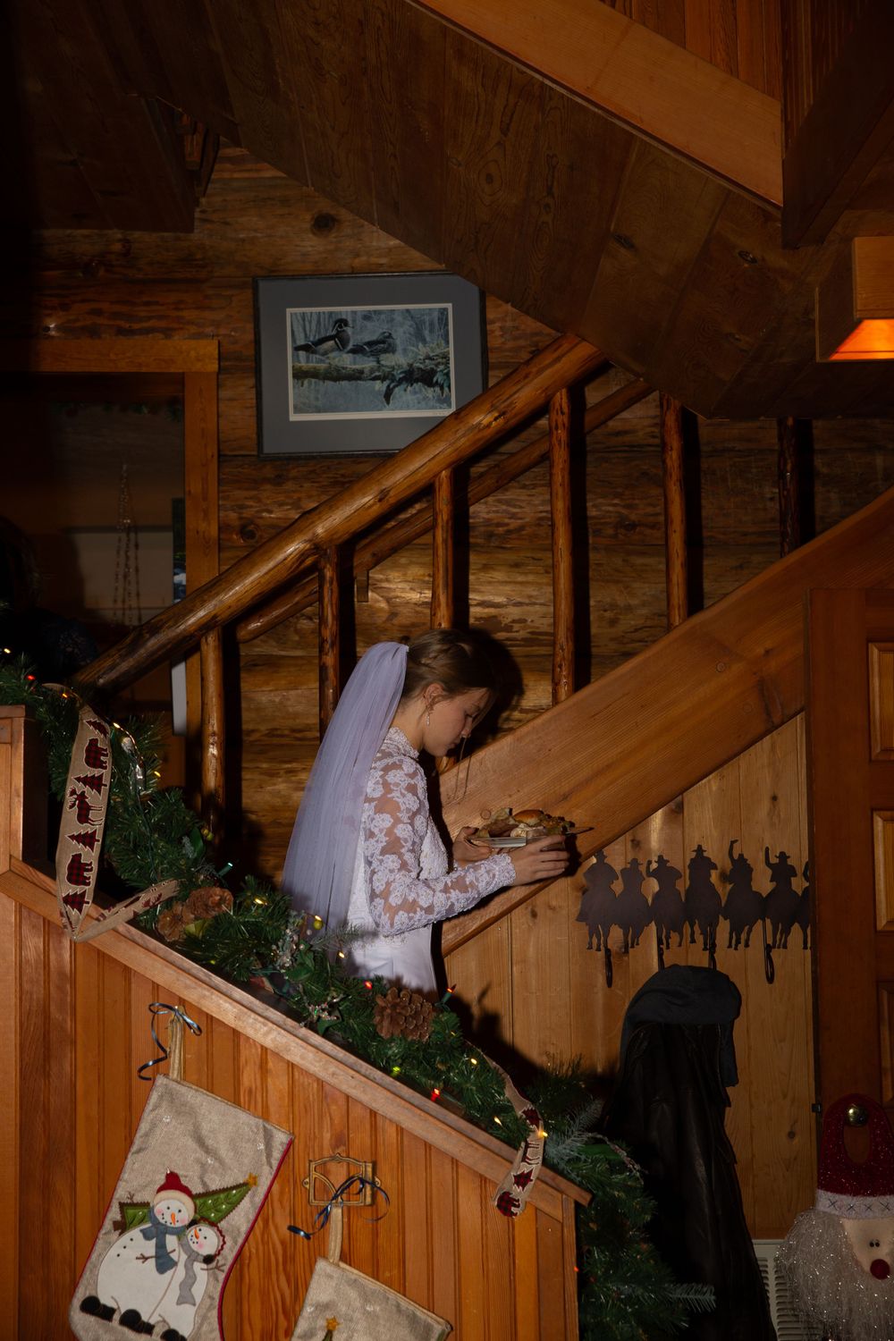 Wedding decor with evergreen garland adorns a wooden staircase in rustic setting.