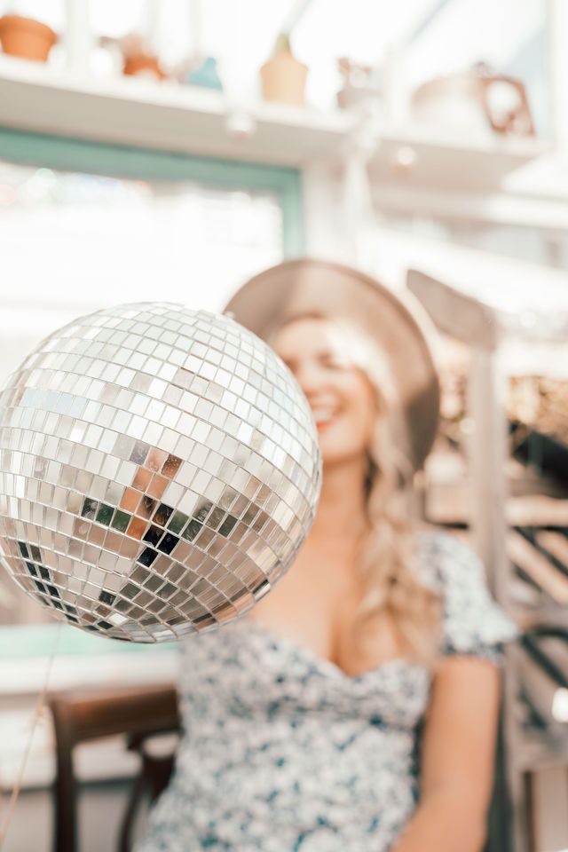 Shimmering disco ball in foreground with blurred interior background.