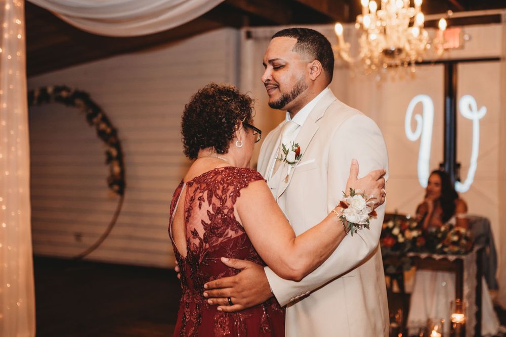 Wedding couple slow dances together under a crystal chandelier at their reception venue.