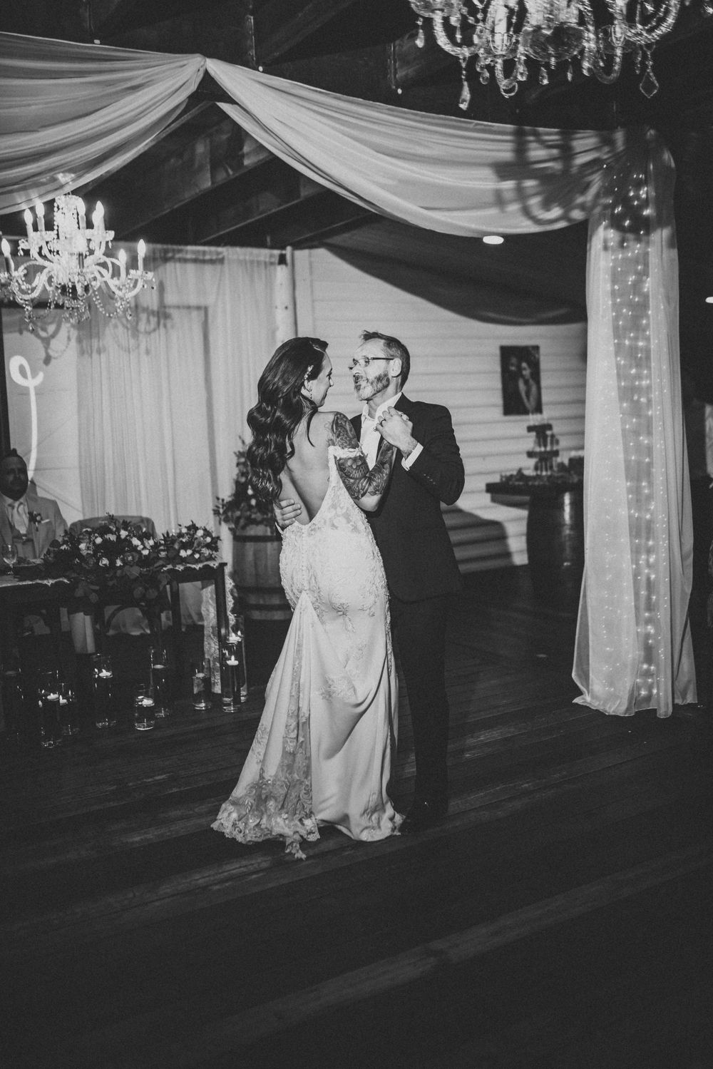 Elegant couple sharing a romantic dance moment under draped fabric and chandeliers.