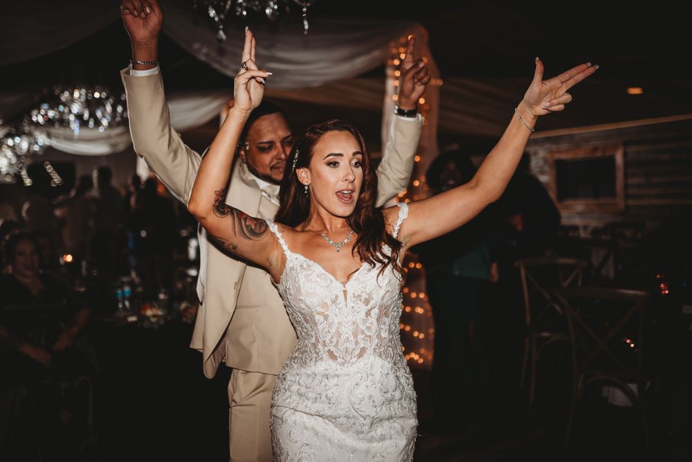 Energetic wedding celebration with dancing and hands raised in celebration.