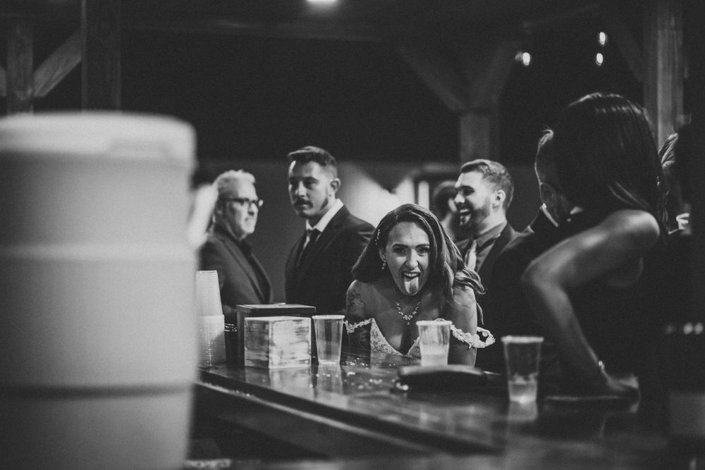 Black and white photo of wedding guests socializing at the reception bar.